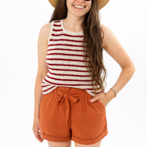Woman_wearing_a_striped_tank_top_brown_shorts_and_a_wide-brimmed_hat_on_a_white_background